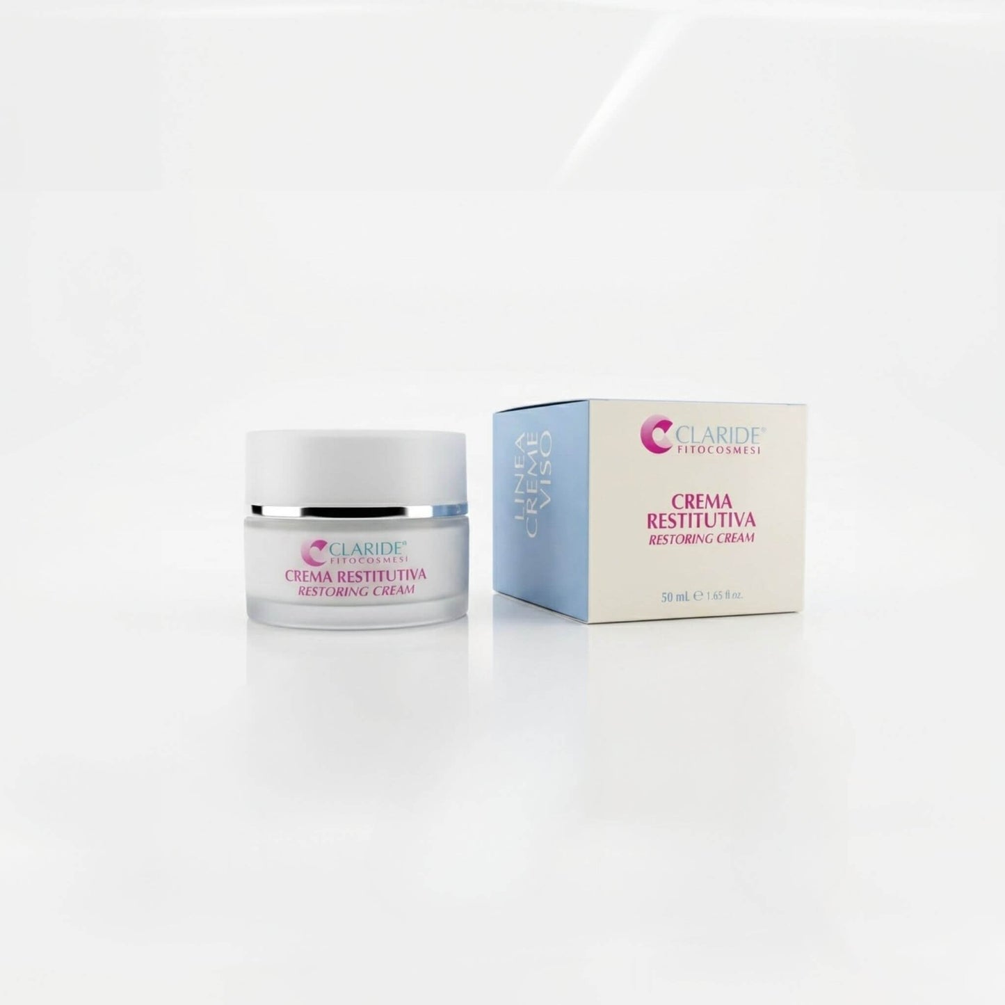 Vasetto in vetro satinato e scatola azzurra e panna della Crema Restitutiva Claride Fitocosmesi. Trattamento viso riparatore e nutriente (Restoring Cream) per restituire compattezza alla pelle stanca e stressata, su fondo bianco con riflesso.