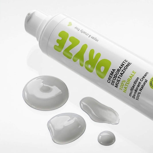 Inquadratura dall'alto del flacone Airless da 50ml di Deodorante DRYZE Claride Fitocosmesi con gocce di crema grigio perla disposte accanto. Una visione ravvicinata che mostra la formula naturale e la praticità del packaging, su fondo bianco lucido.