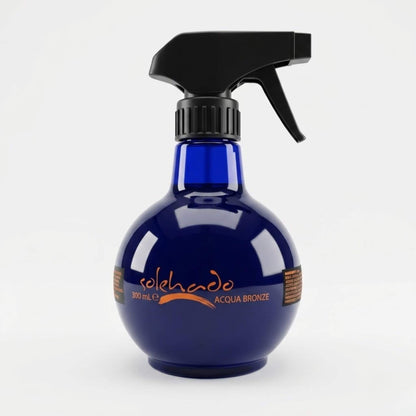 Flacone blu scuro tondeggiante da 300ml con pratico erogatore a pistola dell'Acqua Bronze, linea solare Solehado di Claride Fitocosmesi. Acqua solare rinfrescante in spray per intensificare l'abbronzatura e dissetare la pelle sotto il sole, su fondo bianco.
