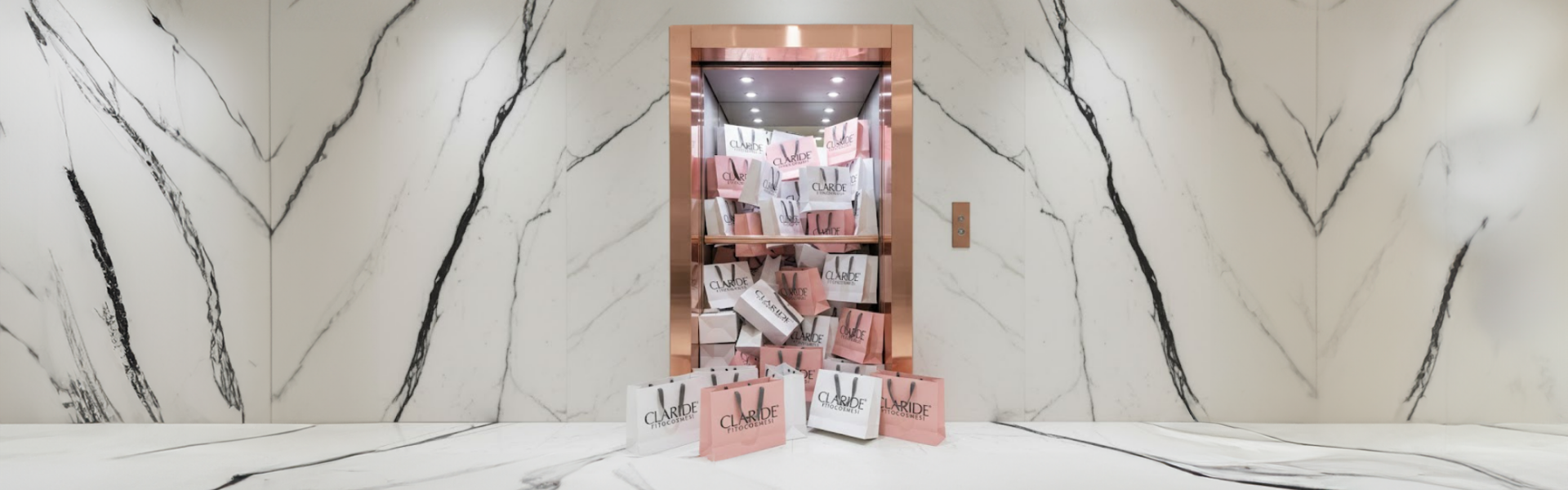 Un ascensore con cornice in rame è stracolmo di numerosi sacchetti di carta bianchi e rosa marchiati "CLARIDE FITOCOSMESI", che fuoriescono e si riversano sul pavimento di una lussuosa hall rivestita in marmo bianco con venature nere.