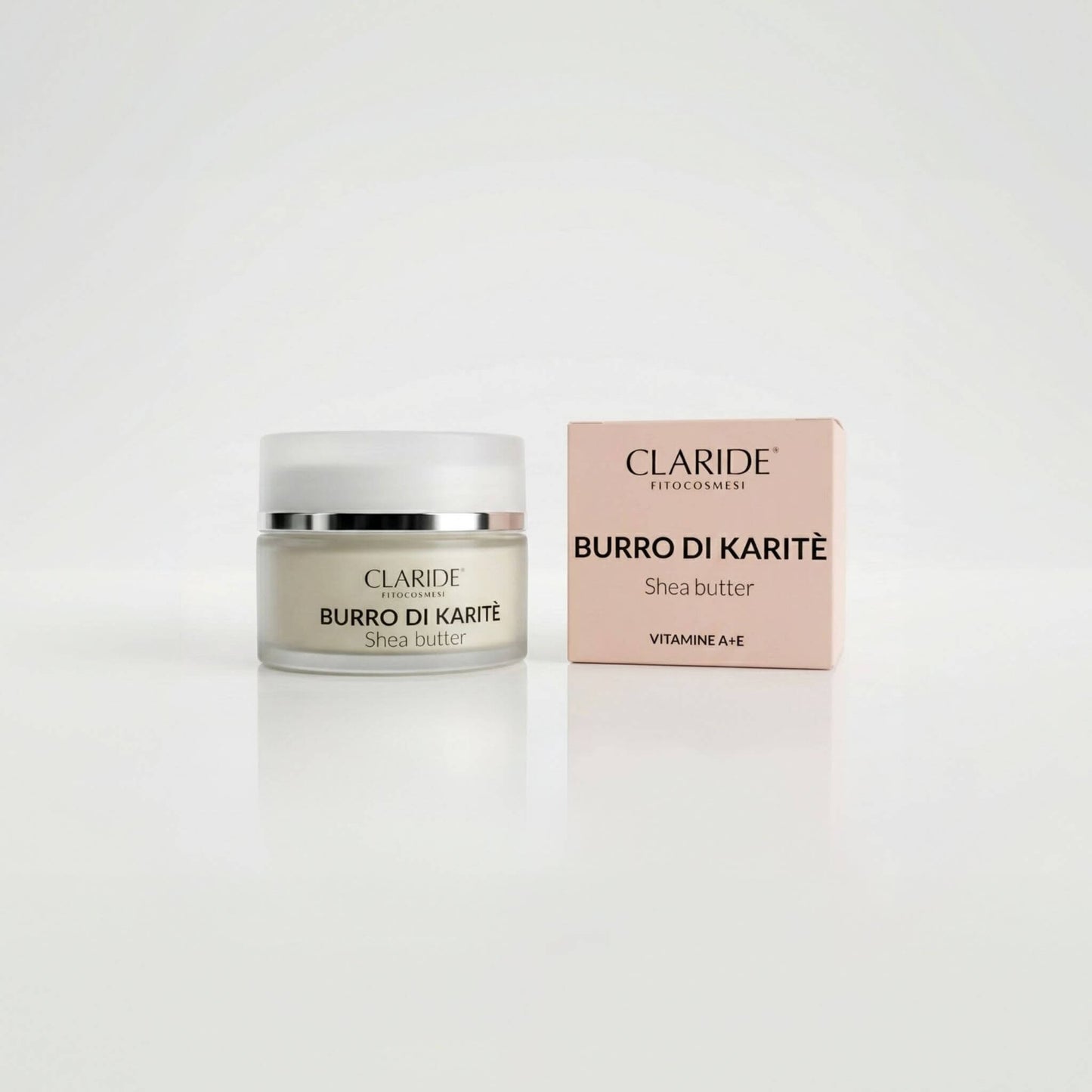 Vasetto in vetro satinato che mostra la texture ricca e scatola rosa del Burro di Karitè Claride Fitocosmesi. Trattamento multiuso super nutriente (Shea Butter) arricchito con Vitamine A ed E per riparare la pelle secca, su fondo bianco con riflesso.