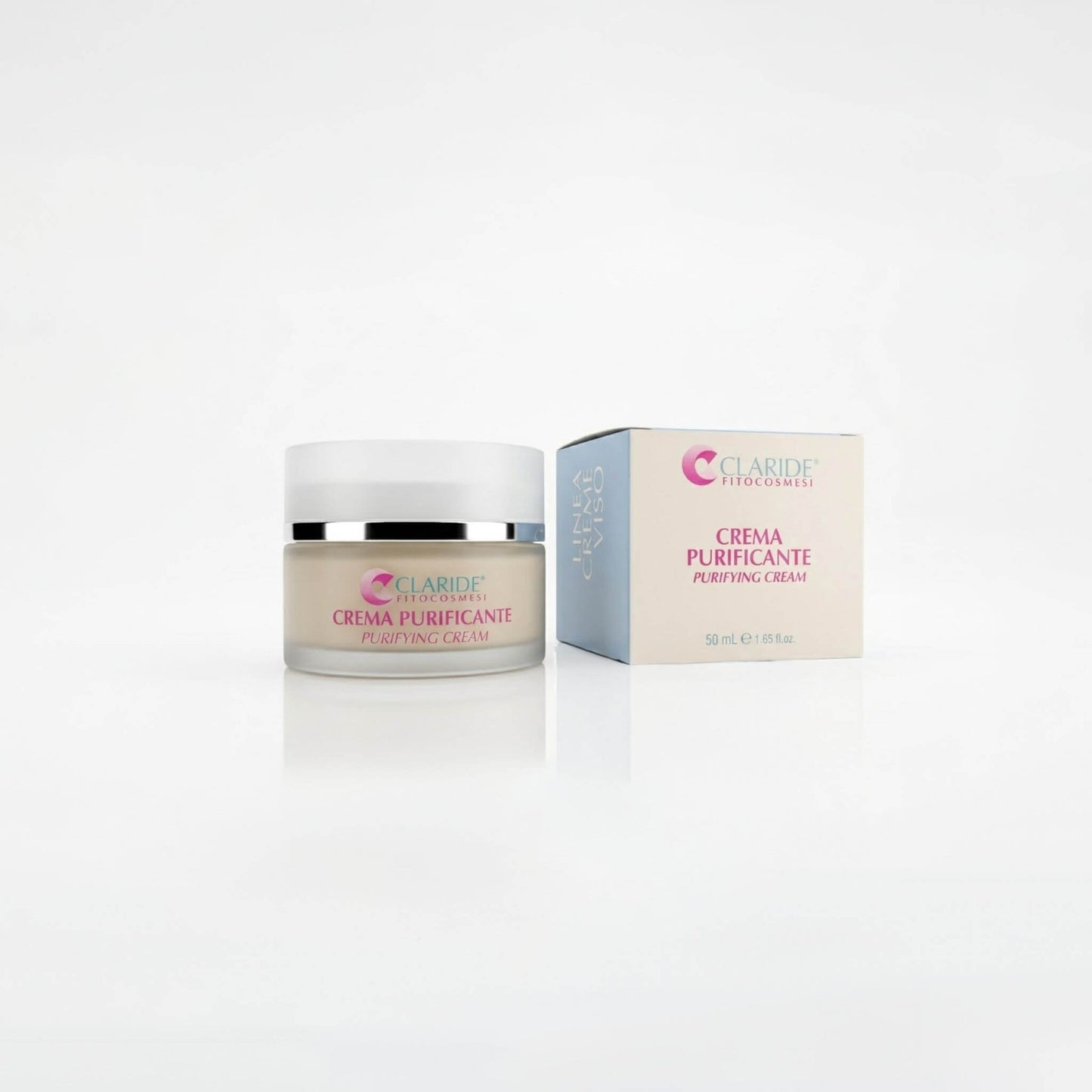 Vasetto in vetro satinato contenente crema dal colore naturale e scatola panna e azzurra della Crema Purificante Claride Fitocosmesi. Trattamento viso opacizzante e sebo-riequilibrante (Purifying Cream) per pelli miste, grasse e con imperfezioni, su fondo bianco con riflesso.