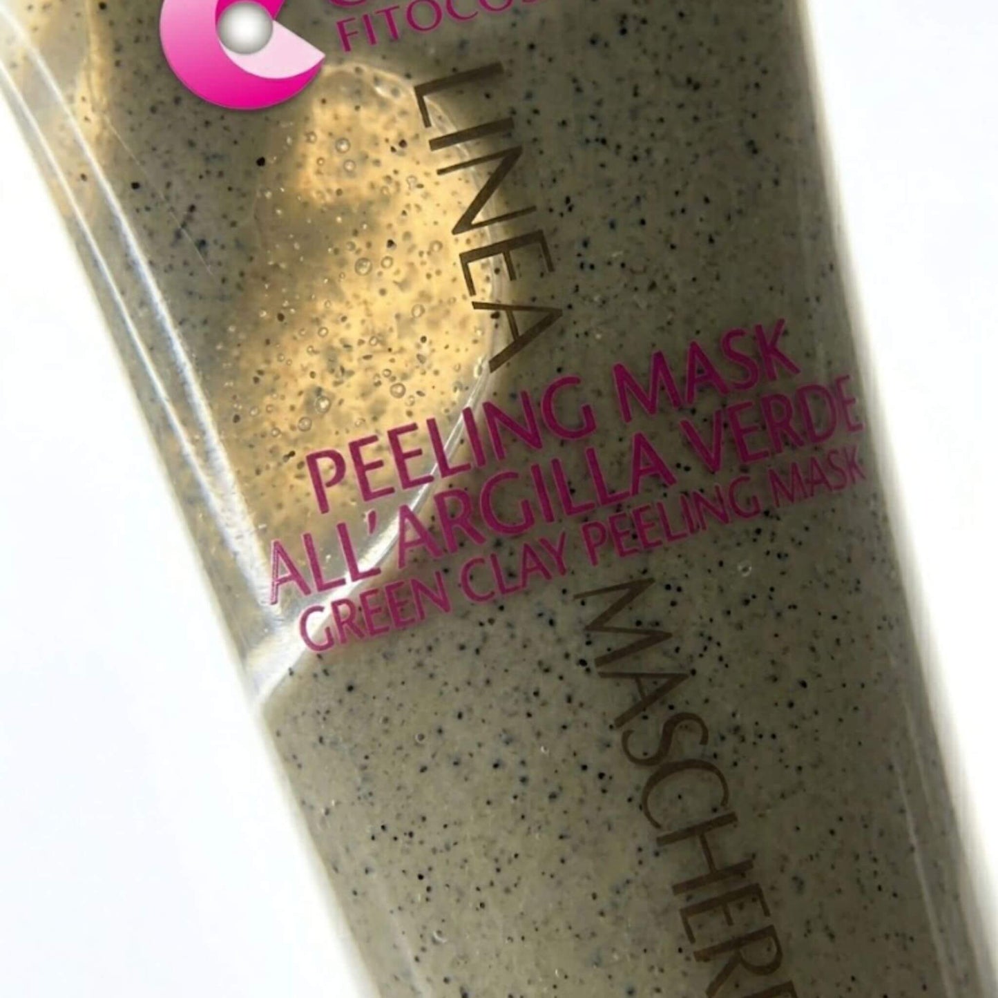 Primo piano macro del tubo della Linea Maschere per il viso a marchio Claride Fitocosmesi. Accanto al packaging sono presenti tre gocce di Peeling Mask all'Argilla Verde che mostrano chiaramente la consistenza in gel ricca di microgranuli esfolianti scuri.