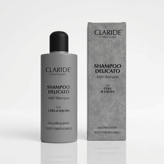 Flacone e scatola grigio satinato dello Shampoo Delicato Claride Fitocosmesi con Cera di Jojoba. Trattamento Mild Shampoo per uso frequente adatto a tutti i tipi di capelli, su fondo bianco con riflesso.